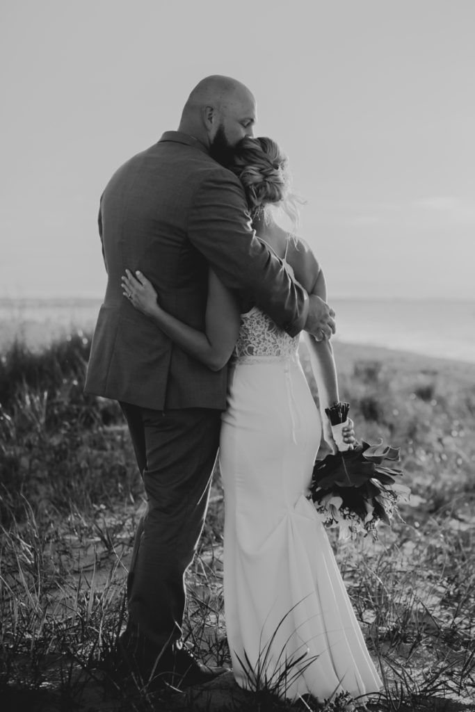 bride and groom hugging on dunes in virginia beach by sharon elizabeth co