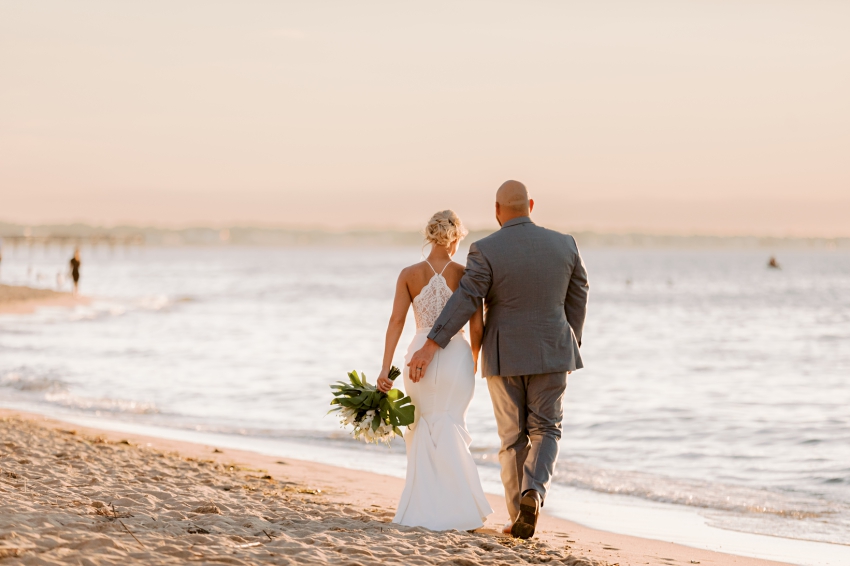 bride and groom walking into sunset by sharon elizabeth co