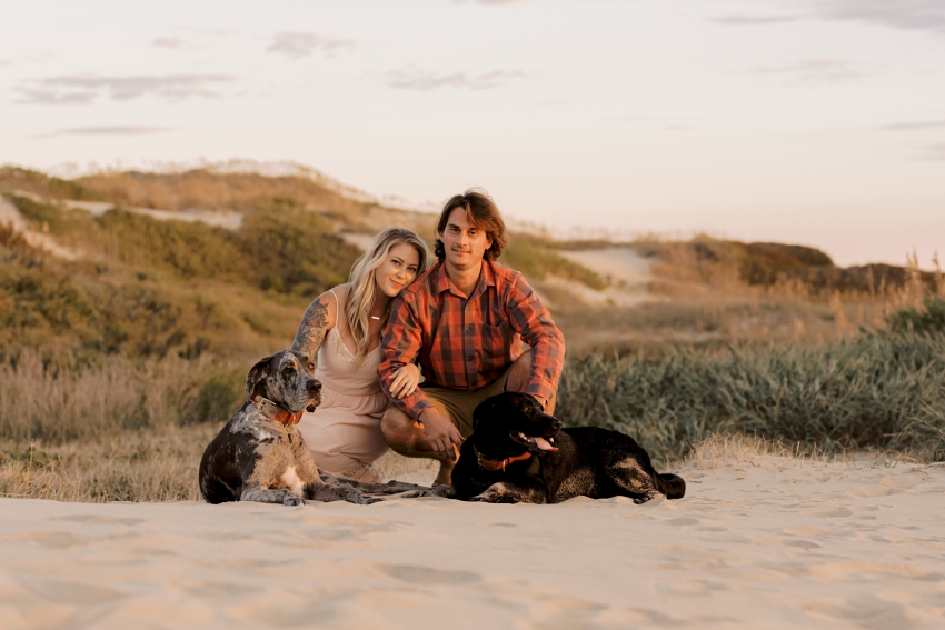 couple with dogs on dunes in nags head, north carolina by sharon elizabeth co