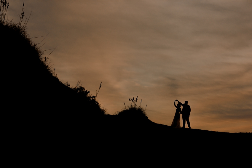 bride and groom dancing silhouette  at sunset on sand dunes