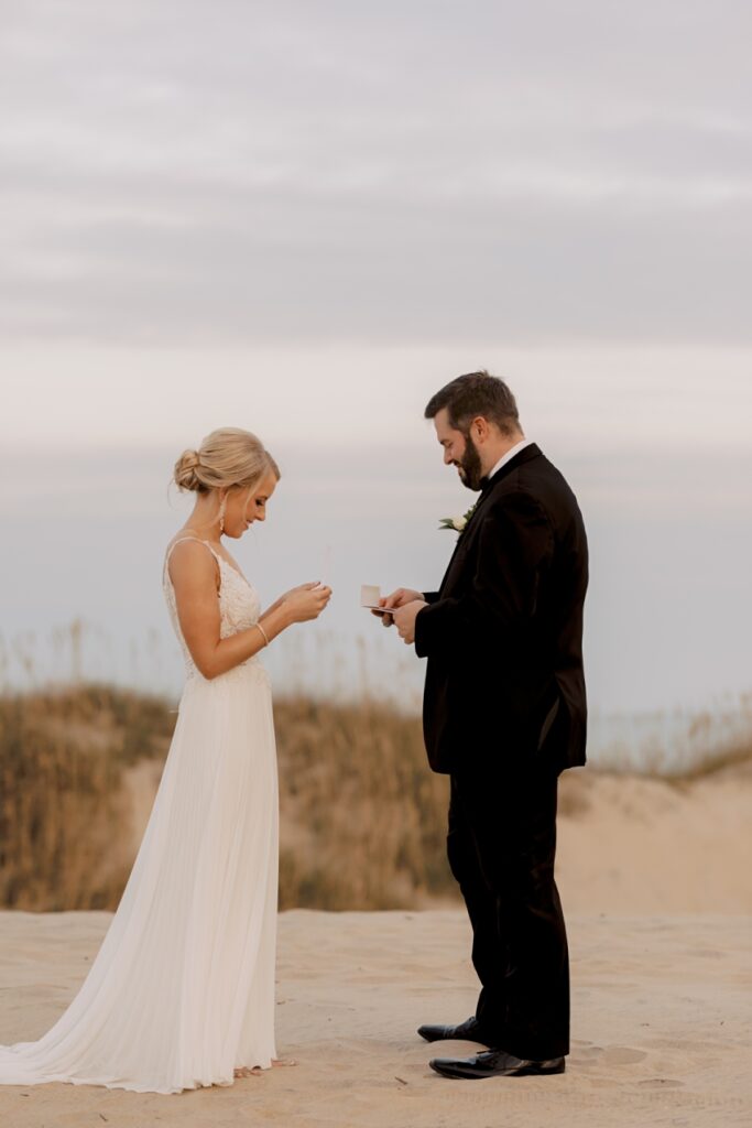 bride and groom reading vows on sand dunes