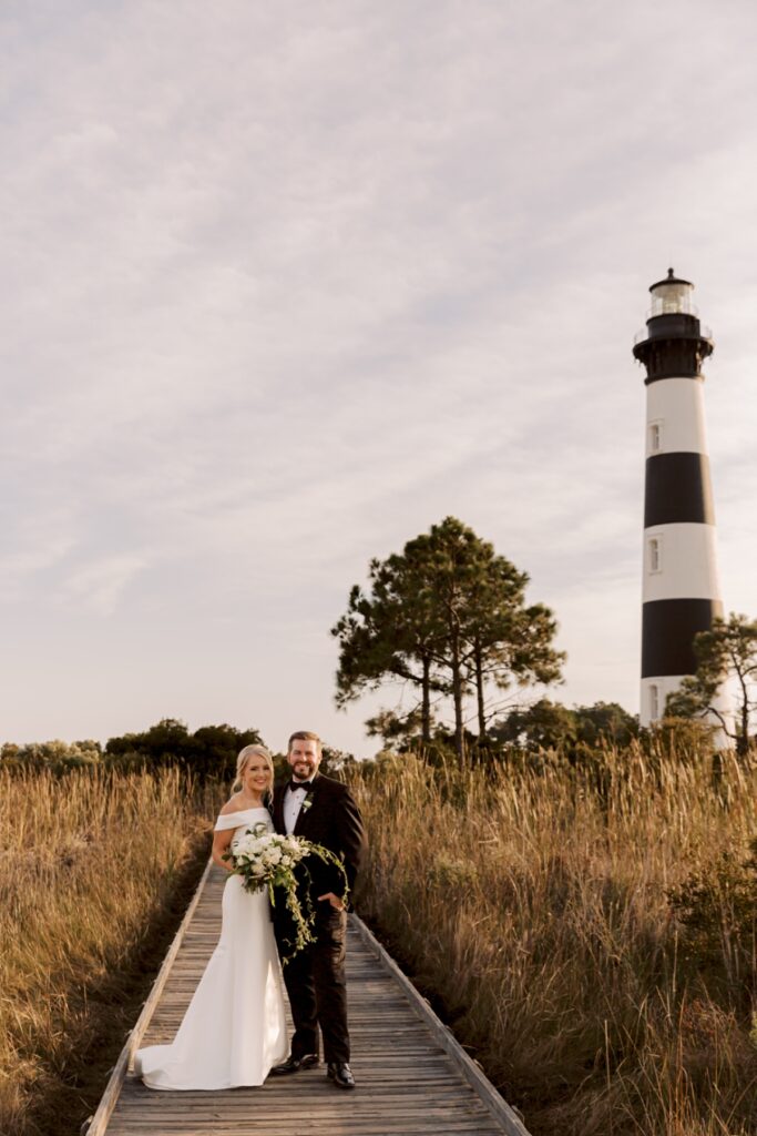 bride and groom on boardwalk by lighthouse