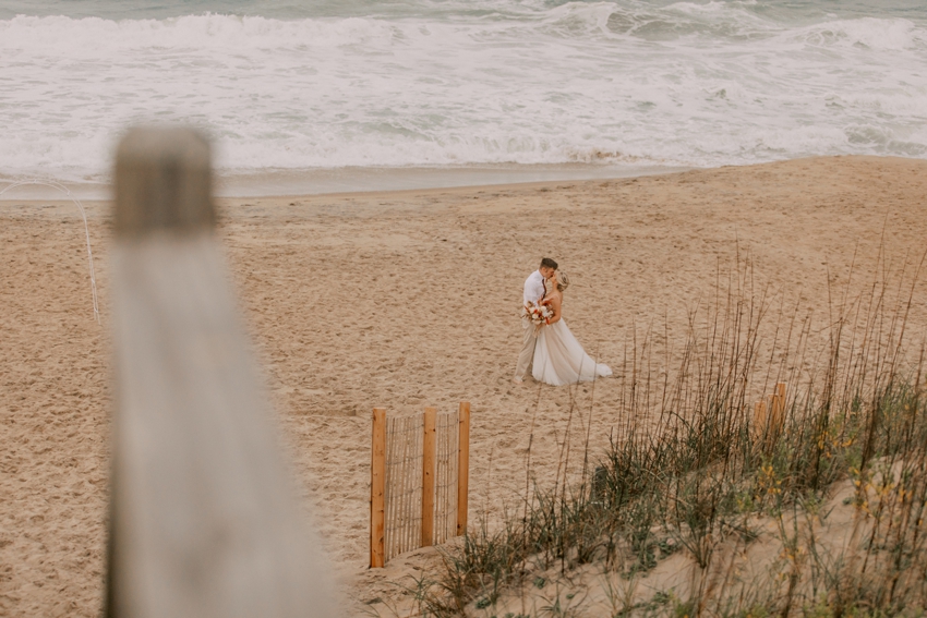 bride and groom hug on Kill Devil Hills beach at sunset