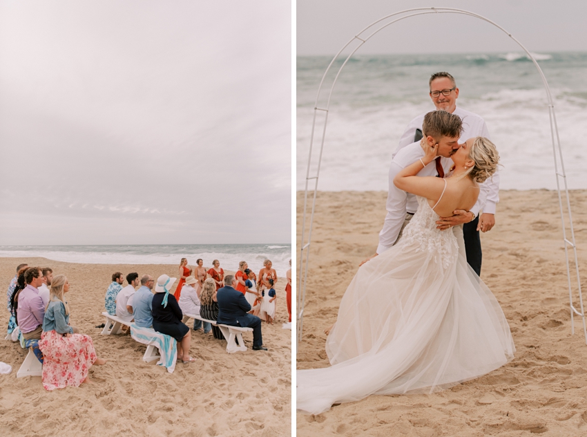 groom kisses bride dipping her during ceremony on sand at Kill Devil Hills