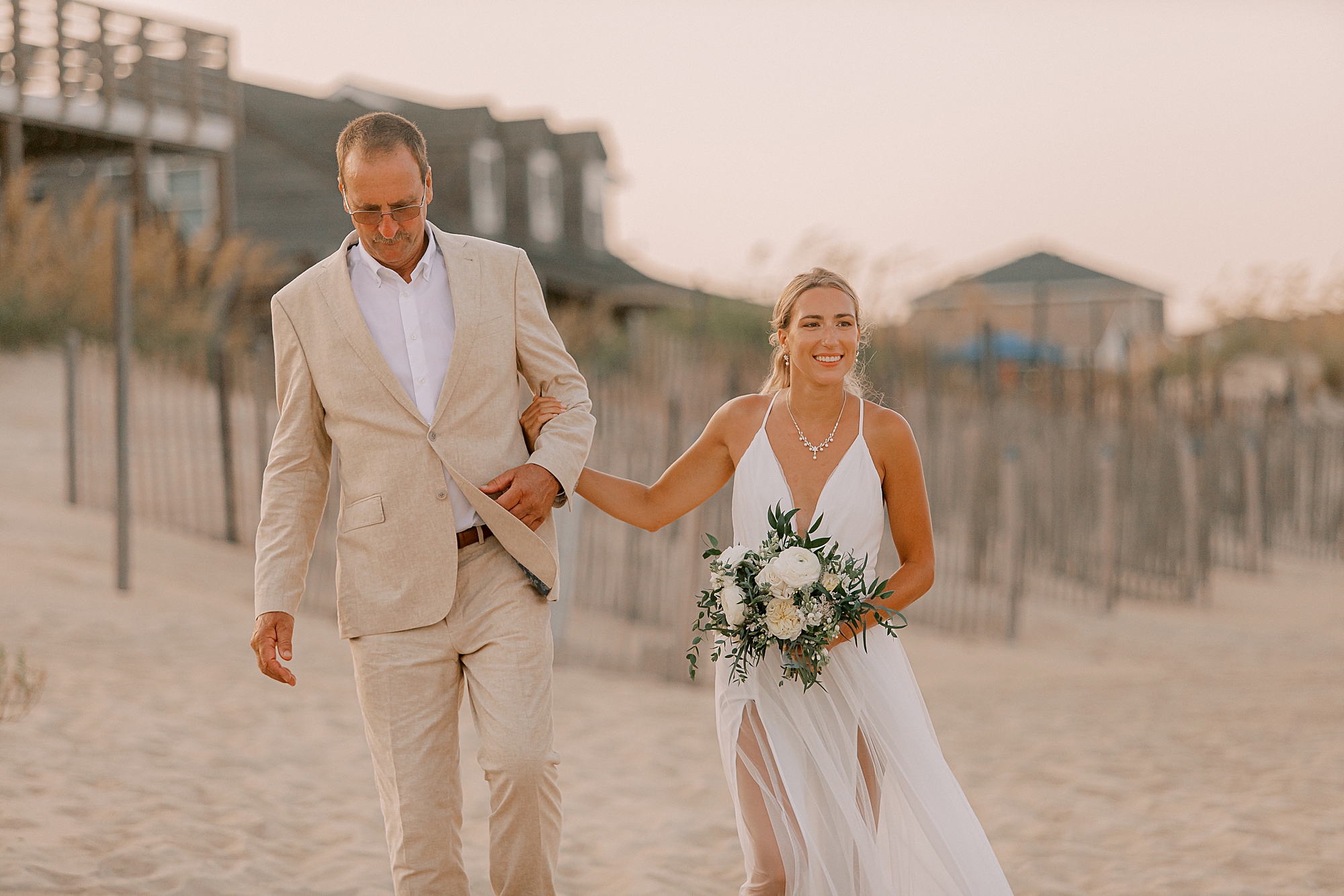 father in tan suit walks bride down for beach ceremony in kill devil hills nc 