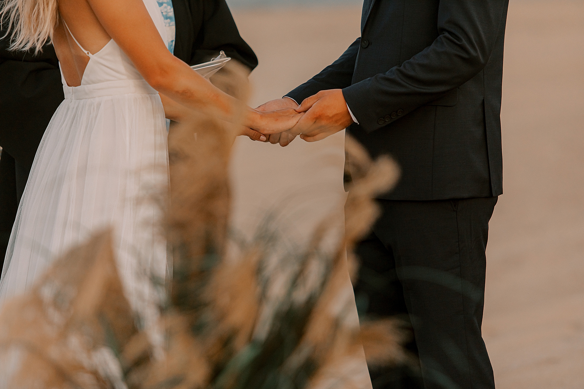 man and woman hold hands during beach ceremony in KDH north Carolina 
