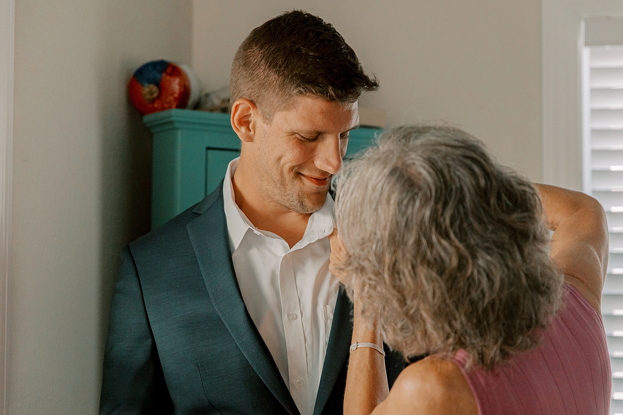 mother puts boutonnière on groom's lapel