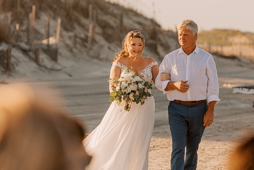 father escorts bride down aisle fore beach wedding ceremony 