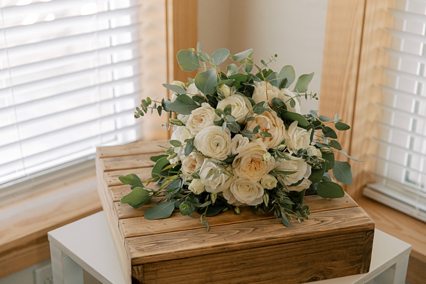 white and peach floral bouquet sits on wooden box