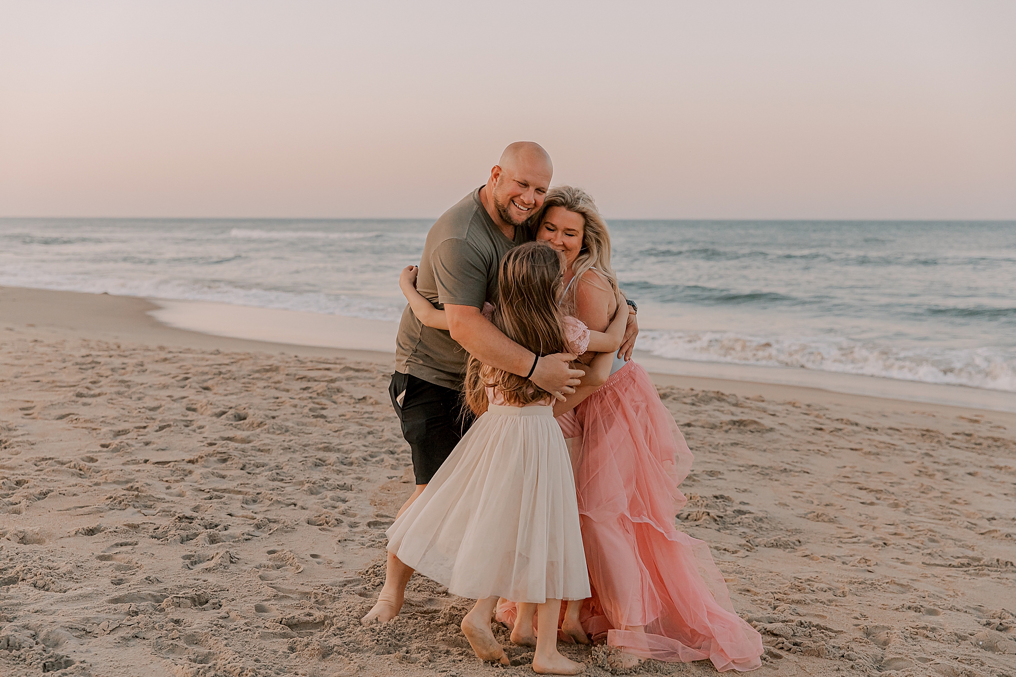 parents hug two daughters at sunset in nags head nc