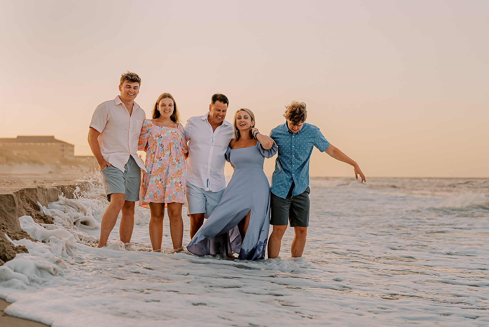 family of five walk through water on the beach during family photos