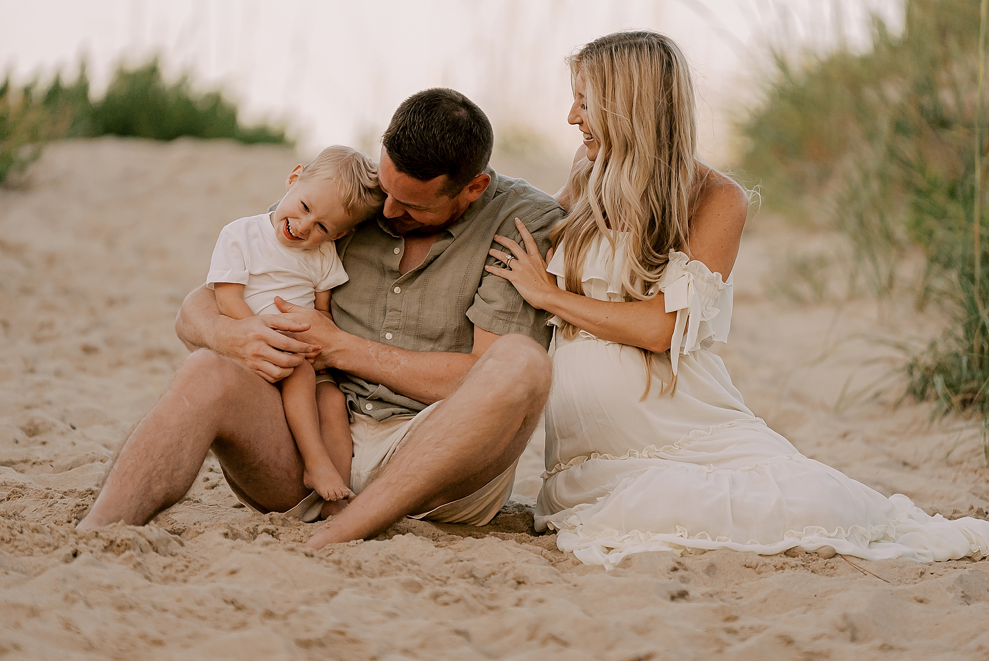 son leans into dad's arm sitting together in the sand in KDH 