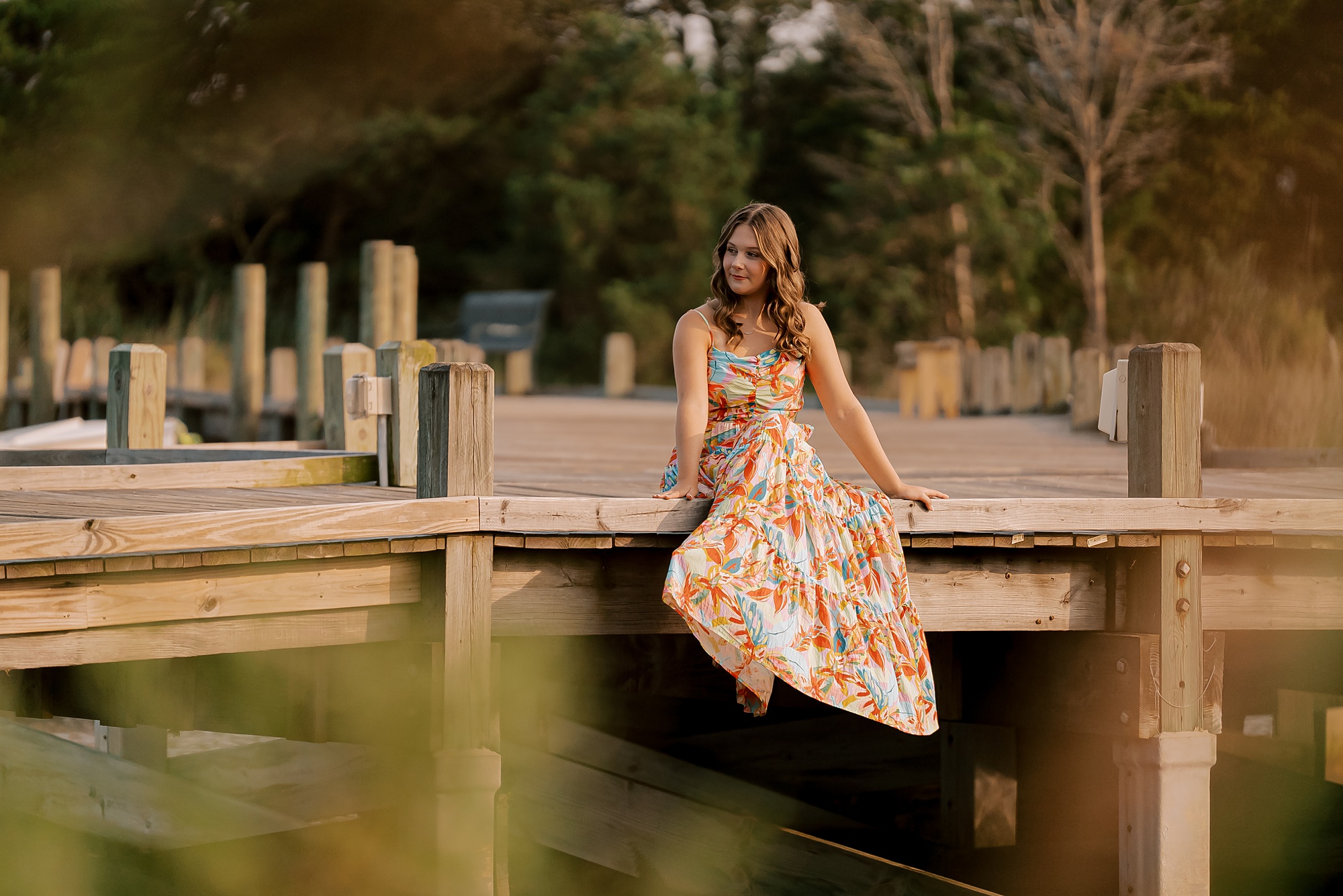 high school girl sits on dock during outer banks senior portraits