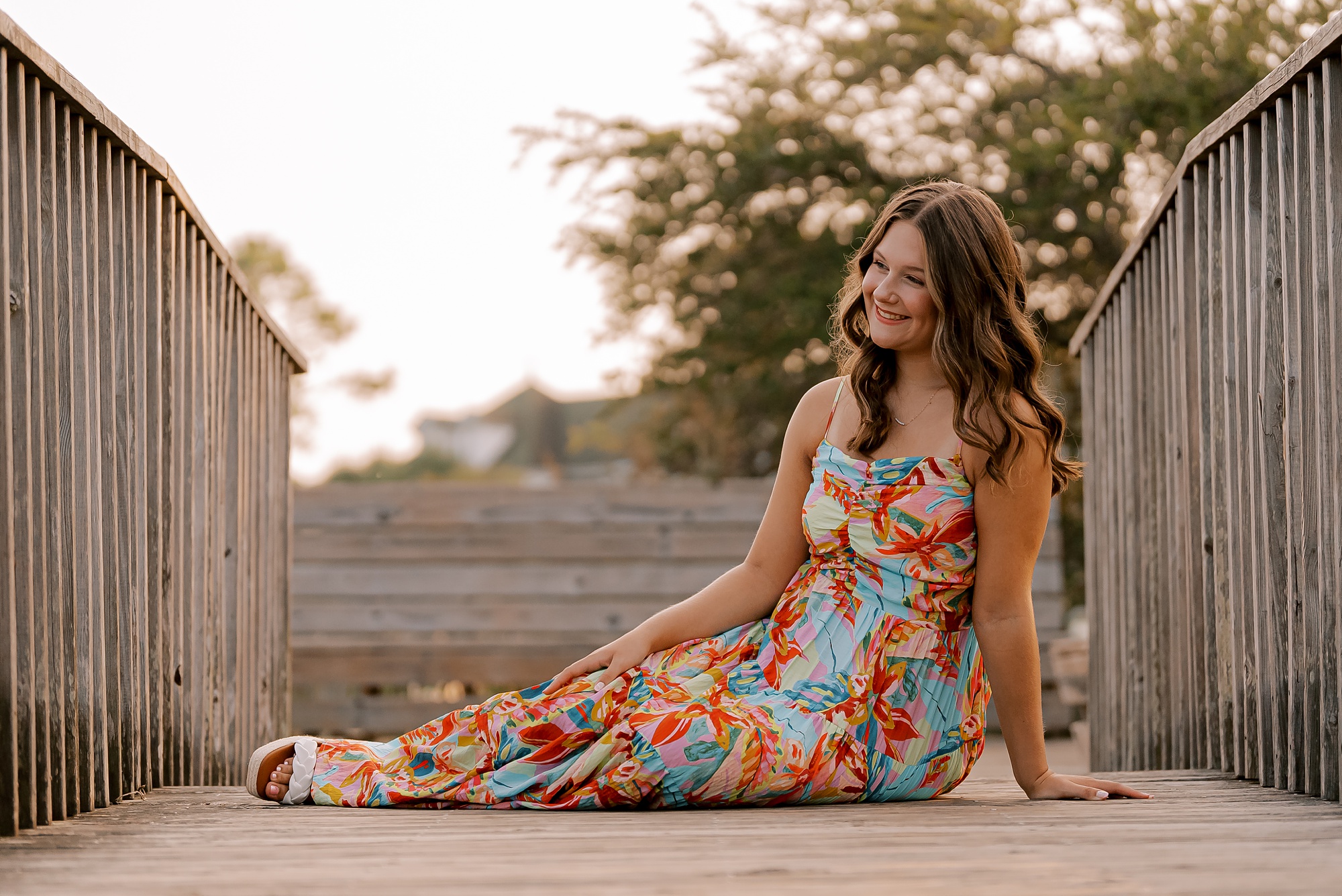 woman sits on wooden bridge near downtown Manteo lighthouse 