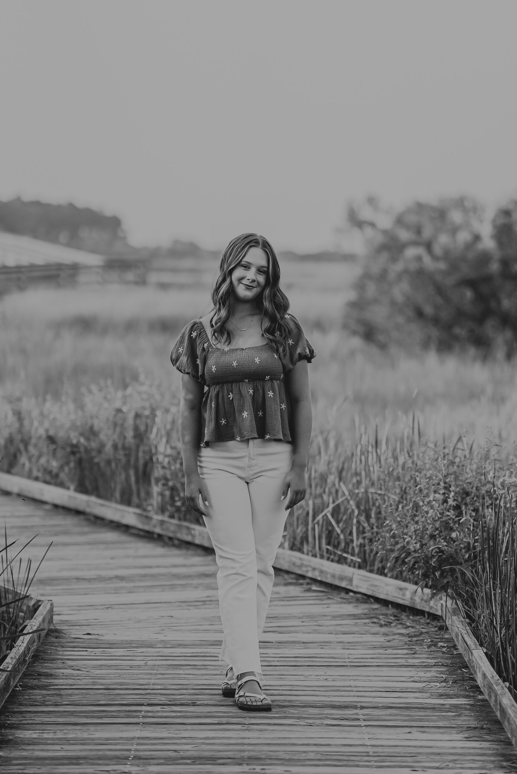 senior stands on wooden walkway during outer banks senior portraits