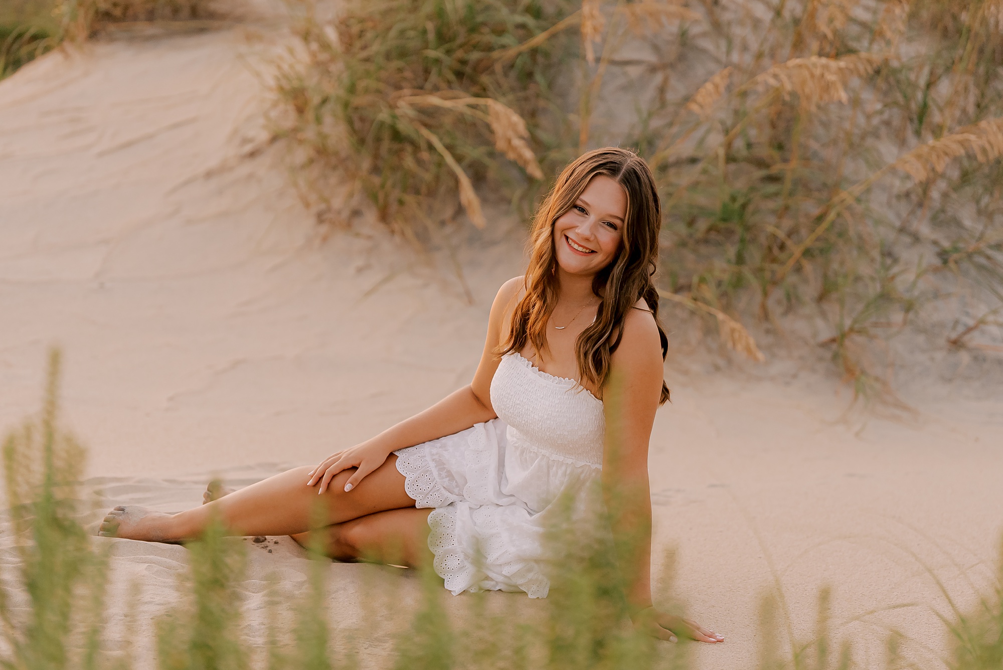 high school senior sits on sand dunes on the Oregon inlet