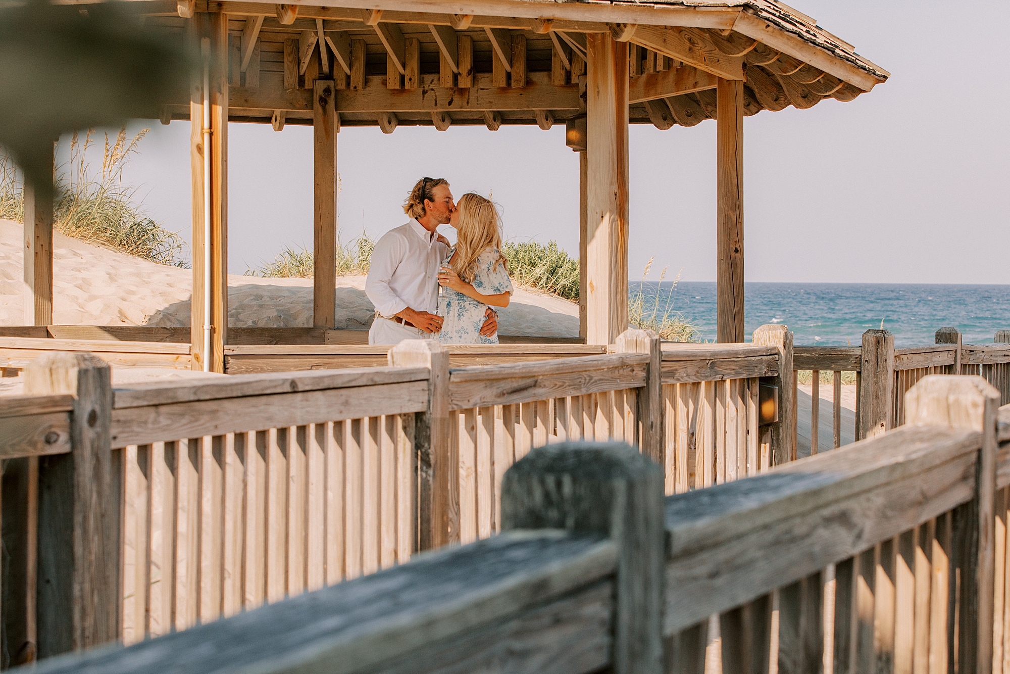 man and woman kiss in wooden gazebo on the outer banks