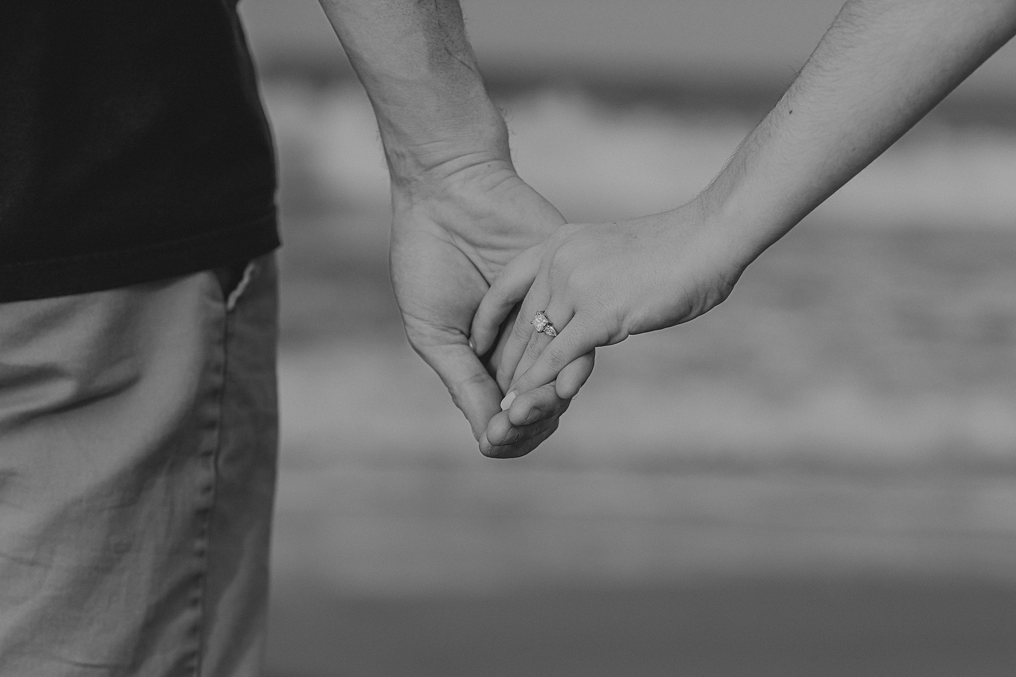 couple holds hands showing off woman's new engagement ring