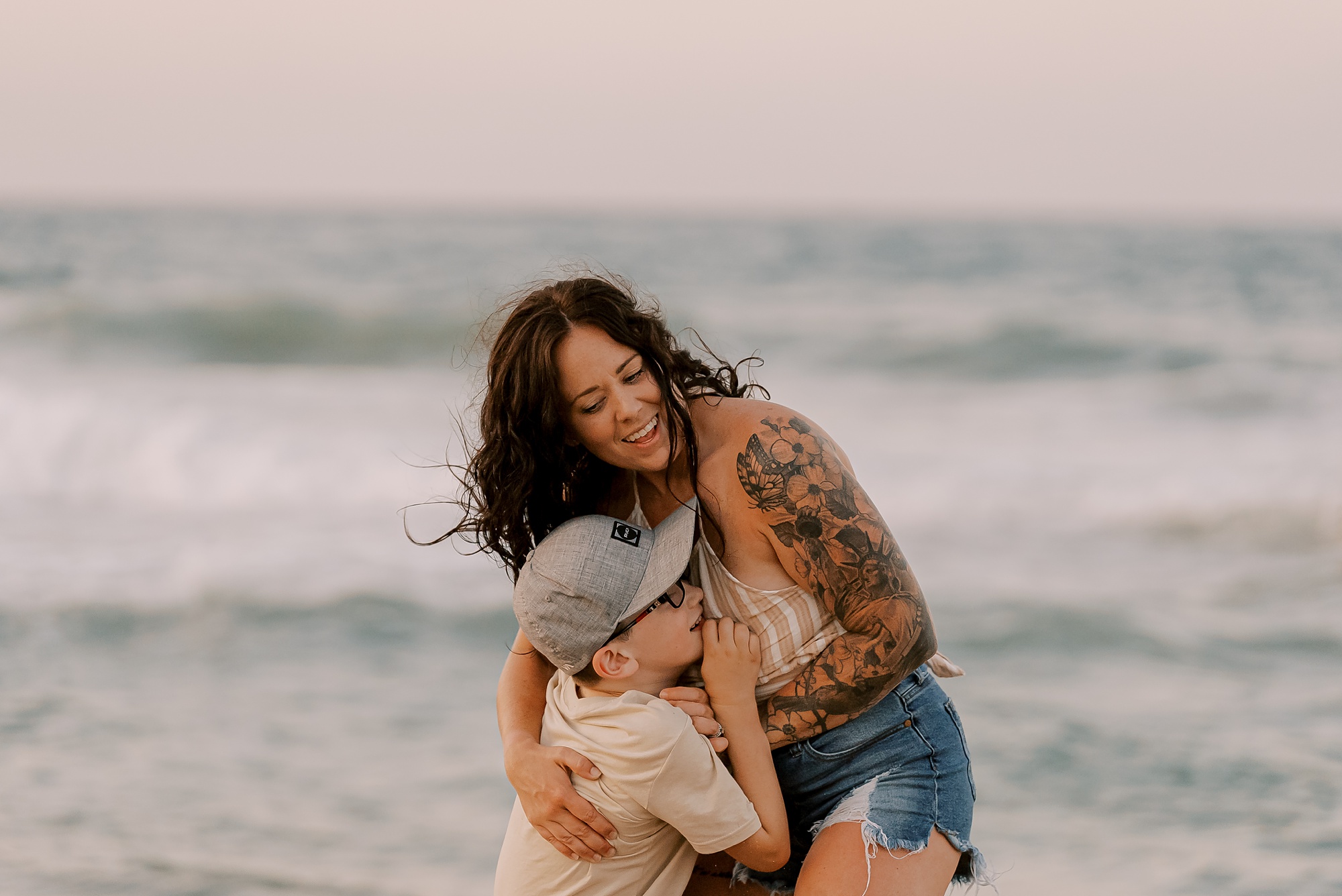 woman hugs son in front of ocean during family photos in the outer banks