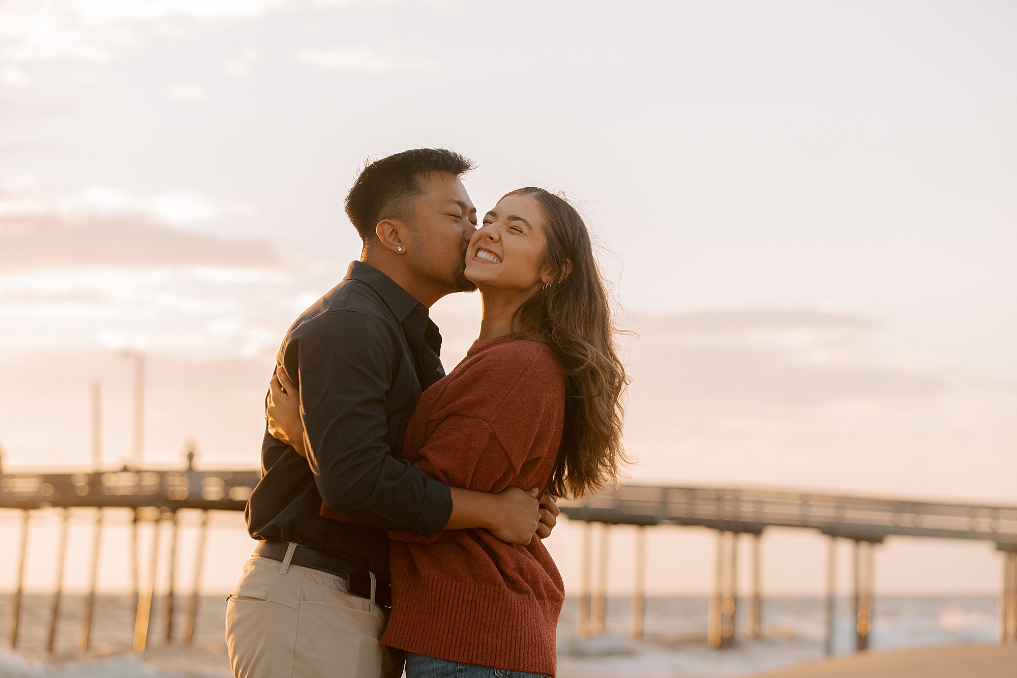 man kisses fiancee on the cheek during nags head beach proposal