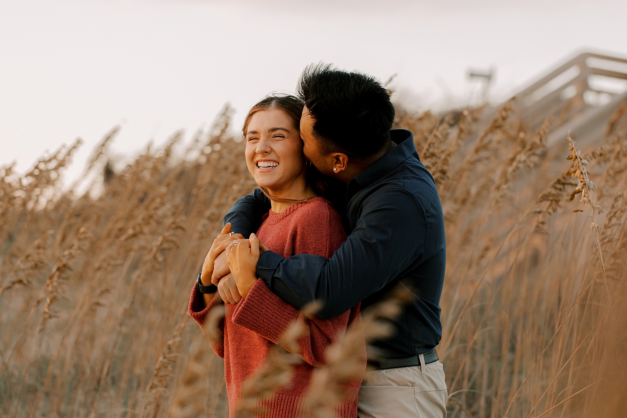 man hugs woman from behind in front of beach glass in nags head nc