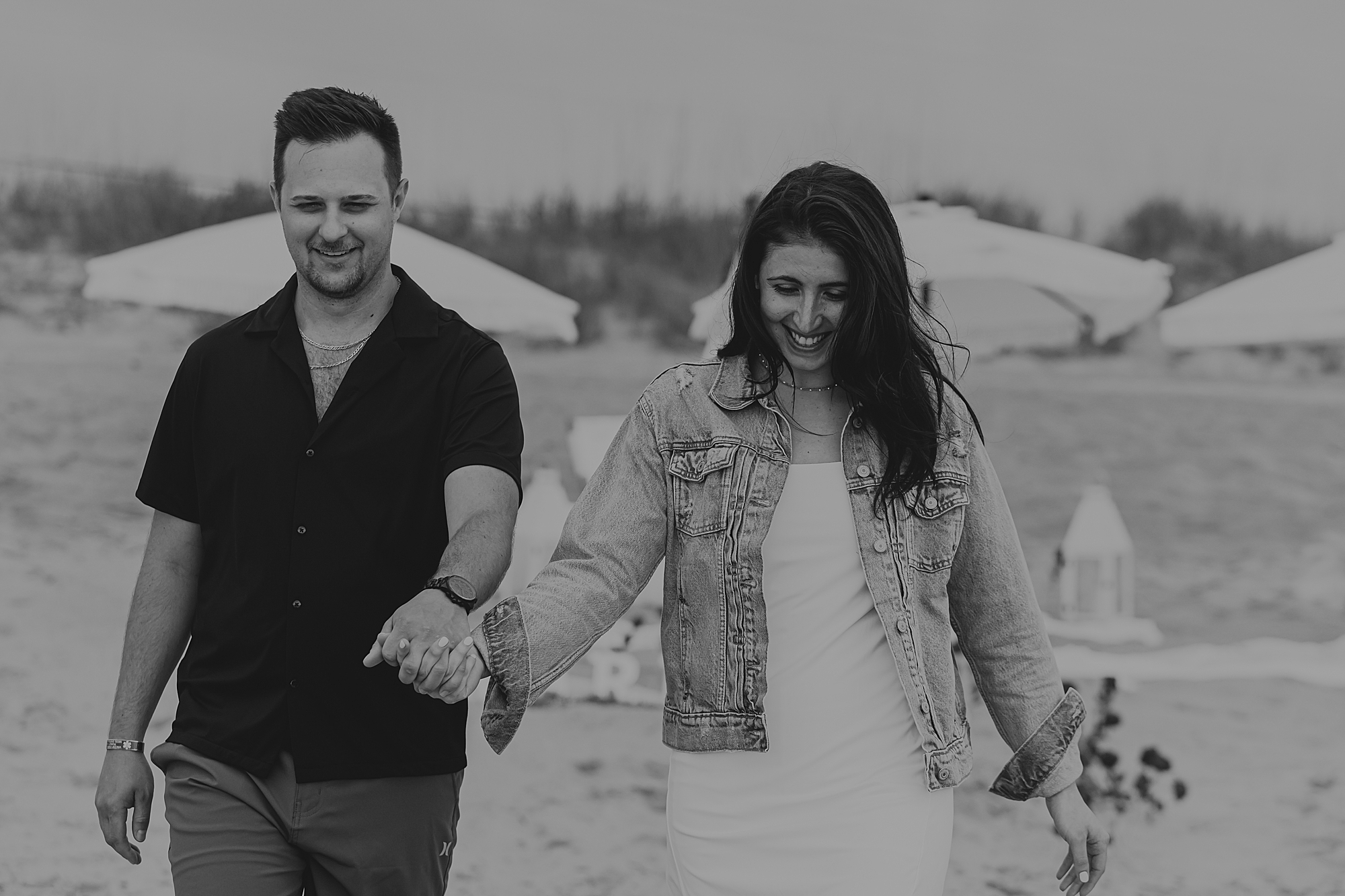 engaged couple holds hands walking down kitty hawk beach