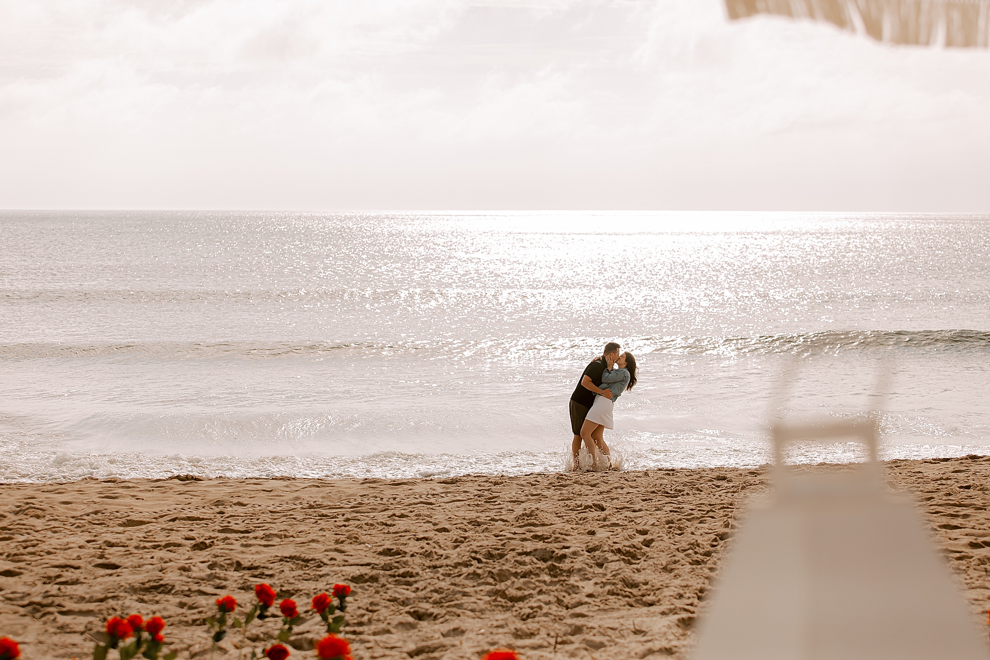 man dips woman kissing her in from of ocean at kitty hawk beach